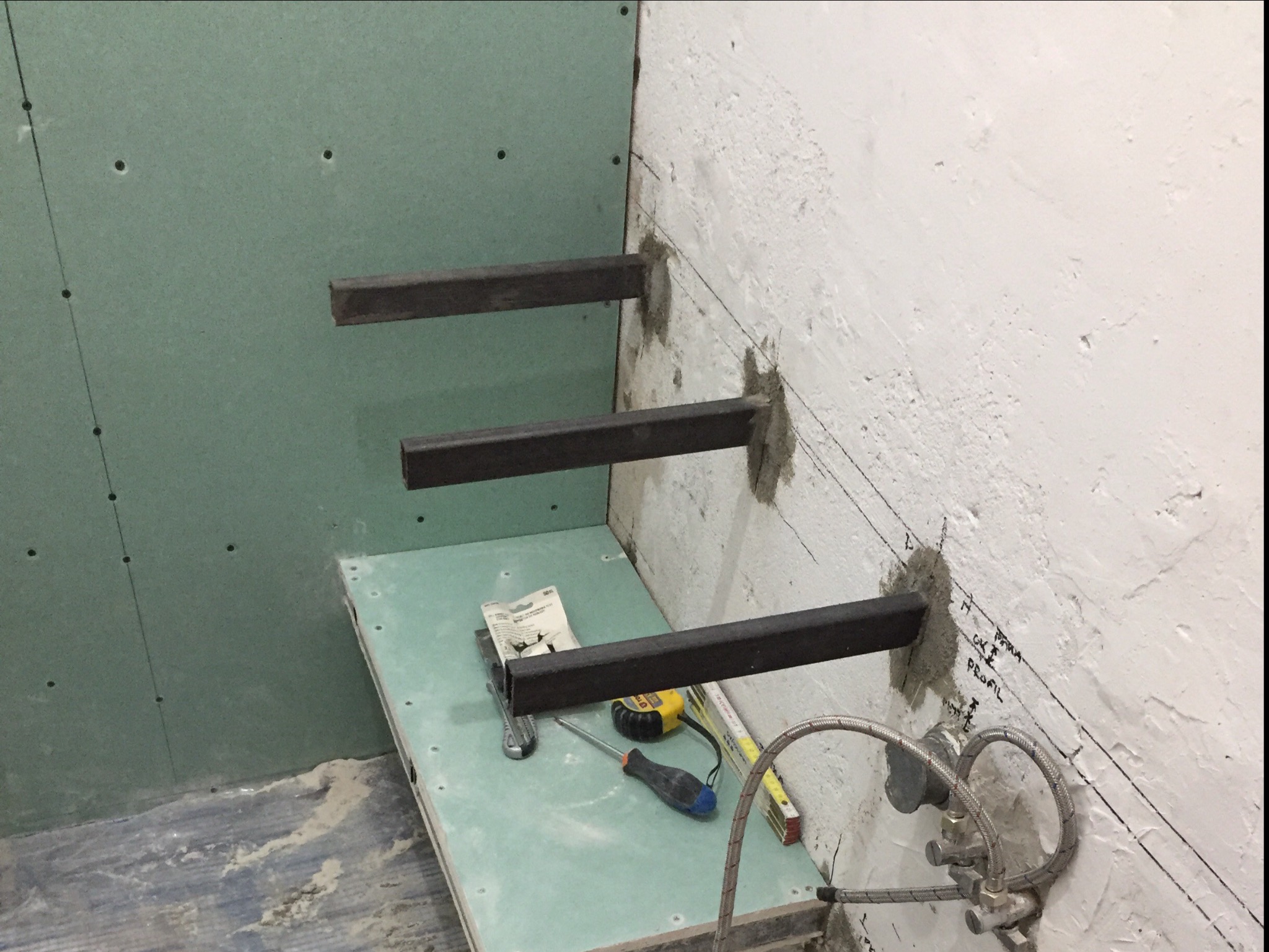 Montaż metalowych profili do ściany w łazience, przygotowanie pod zabudowę z płyt kartonowo-gipsowych, widoczne narzędzia i elementy instalacji wodnej.