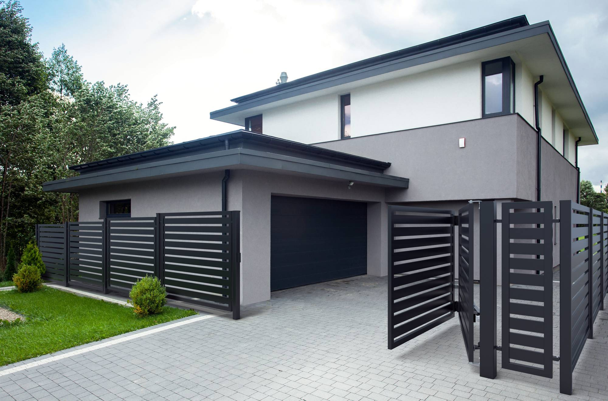 Nowoczesna posesja z grafitowym ogrodzeniem panelowym z poziomymi szczeblami i otwartą bramą wjazdową, na tle domu z garażem i kostki brukowej.
