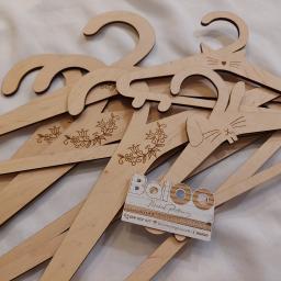 BalOO Michał Piotrowicz - Drewniane wieszaki laserowo wycinane i grawerowane, z motywami zwierzęcymi (kot, królik) i roślinnymi, ułożone na białym tle, z wizytówką firmy Baloo.