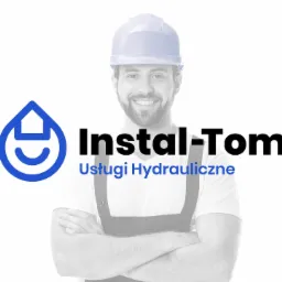 Uśmiechnięty hydraulik w białym kasku i roboczym ubraniu na tle logo firmy Instal-Tom Usługi Hydrauliczne.