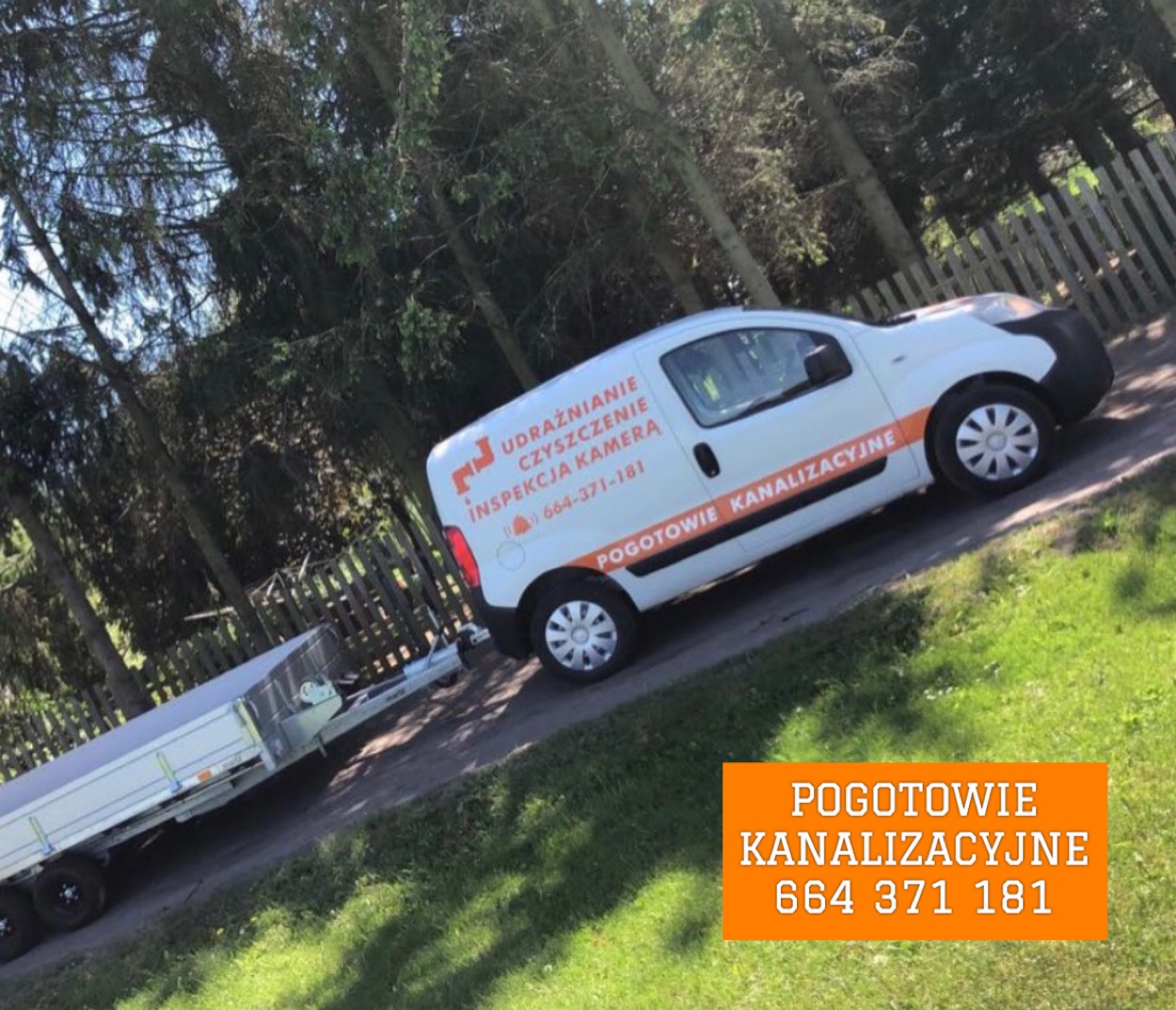 Biała furgonetka z pomarańczowymi napisami 'Udrażnianie, czyszczenie, inspekcja kamera, pogotowie kanalizacyjne' i numerem telefonu, zaparkowana na trawniku obok przyczepy z plandeką, w tle drzewa...