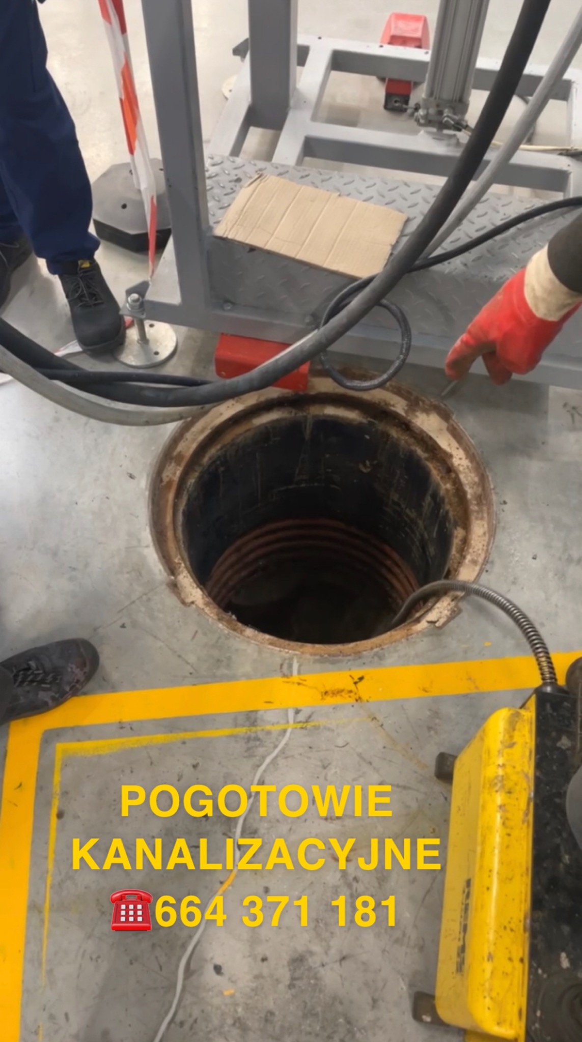 Otwarty właz kanalizacyjny z widoczną spiralą wewnątrz, obok narzędzie do czyszczenia, pracownik w rękawicy wskazuje na otwór.