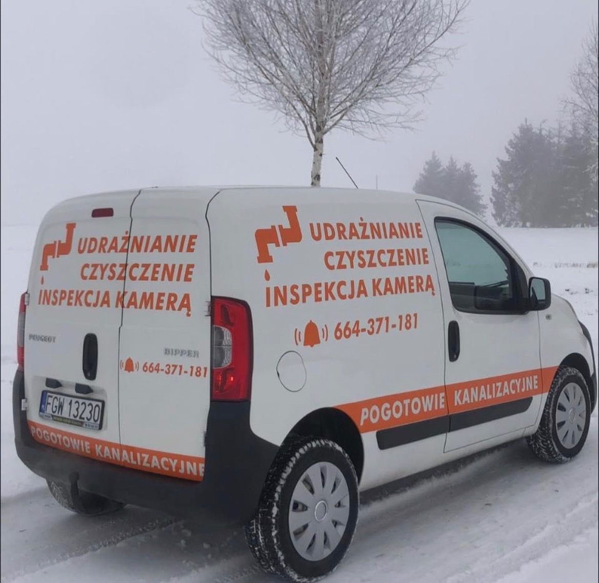 Biały samochód dostawczy Peugeot Bipper z pomarańczowym logo firmy hydraulicznej oferującej czyszczenie, inspekcję kamerą i pogotowie kanalizacyjne, zaparkowany na ośnieżonym terenie w pochmurny...