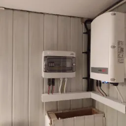 Rozdzielnica elektryczna KENO i falownik SolarEdge zamontowane na ścianie z paneli w Libiążu. Widoczne przewody i kable w białych listwach.