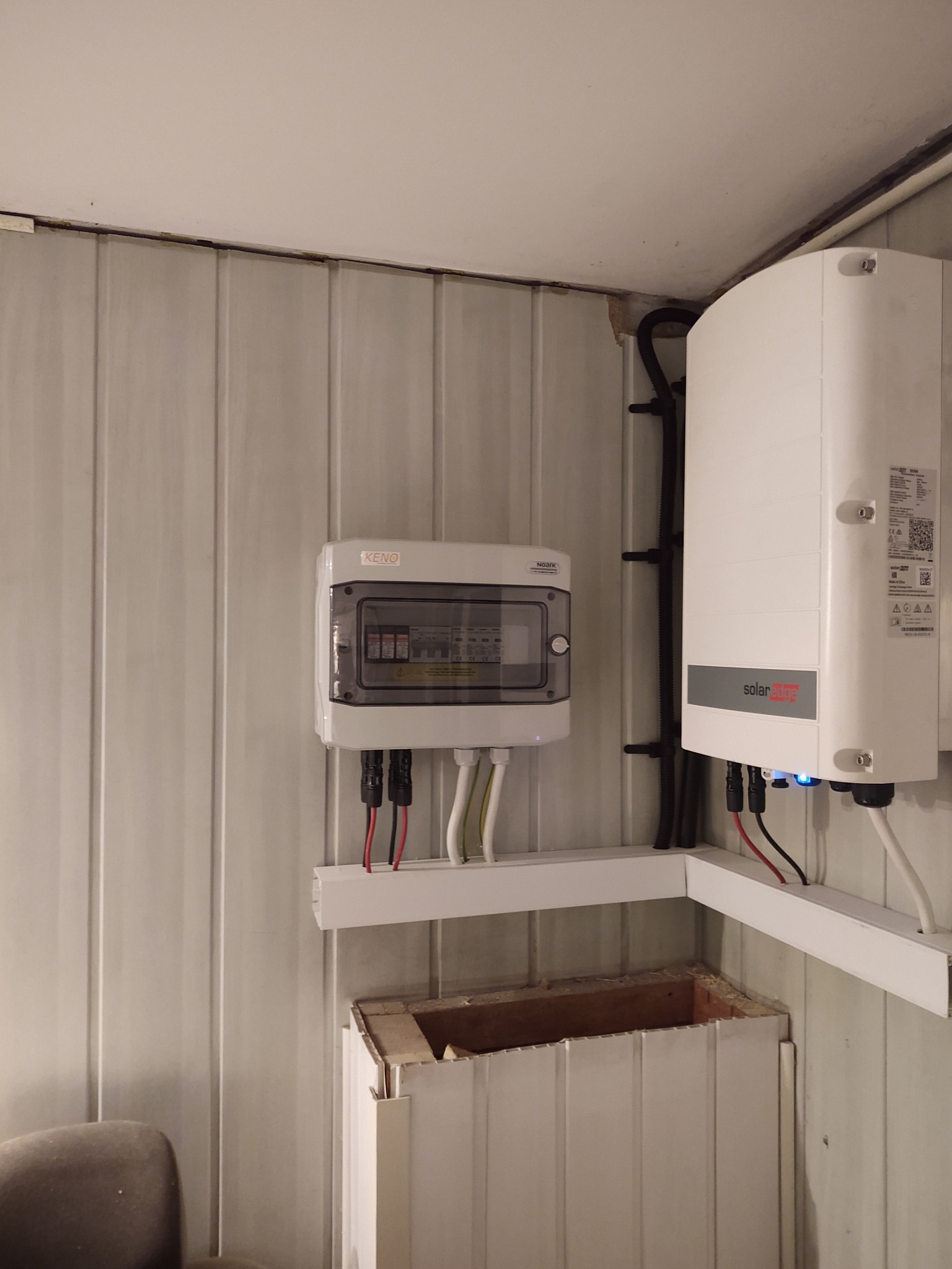Rozdzielnica elektryczna KENO i falownik SolarEdge zamontowane na ścianie z paneli w Libiążu. Widoczne przewody i kable w białych listwach.