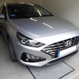 Srebrny Hyundai i30 kombi, widok z przodu, zaparkowany w jasnym pomieszczeniu, na podłodze szara mata.