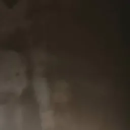 Świeżo nałożona, mokra warstwa szarego tynku na ścianie, widoczne zacieki i różnice w fakturze.