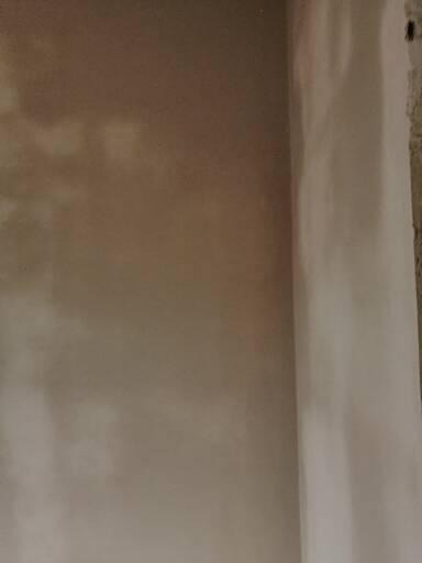 Świeżo nałożona, jasna warstwa gładzi na ścianie w trakcie prac wykończeniowych w Mińsku Mazowieckim, widoczne nierówności i niedoskonałości powierzchni przed ostatecznym szlifowaniem.