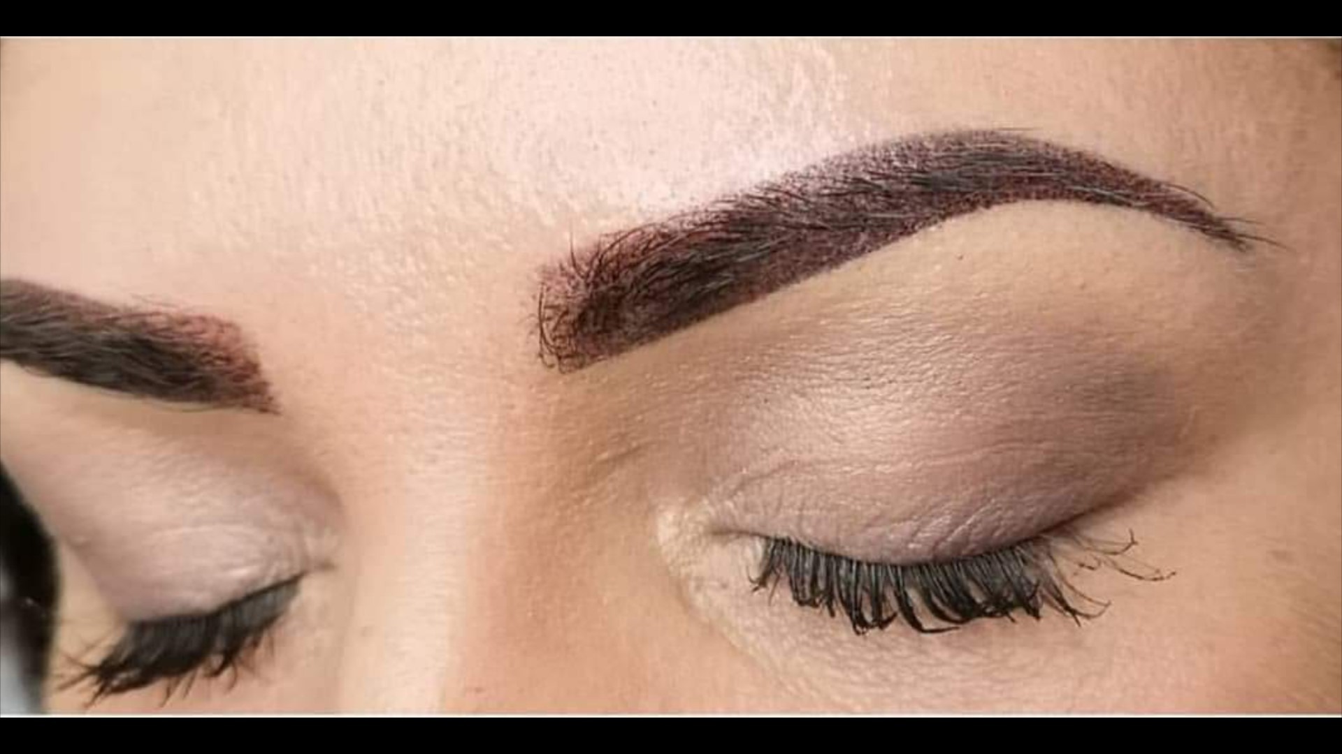 Zbliżenie na oko z makijażem permanentnym brwi metodą pudrową, widoczne naturalne włoski i pigmentacja skóry.
