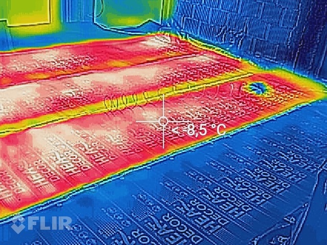 Termowizyjne zdjęcie ogrzewania podłogowego, widoczne rozłożenie ciepła na powierzchni, z zaznaczoną temperaturą 8,5 stopni Celsjusza i logo FLIR.