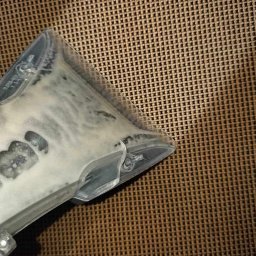 Szałek Krzysztof Szałkowski - Przezroczysta końcówka odkurzacza piorącego z resztkami piany na tle brązowej, plecionej tkaniny.