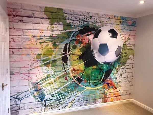 Fototapeta na ścianie z motywem piłki nożnej na tle muru z cegieł pokrytego kolorowymi plamami farby.