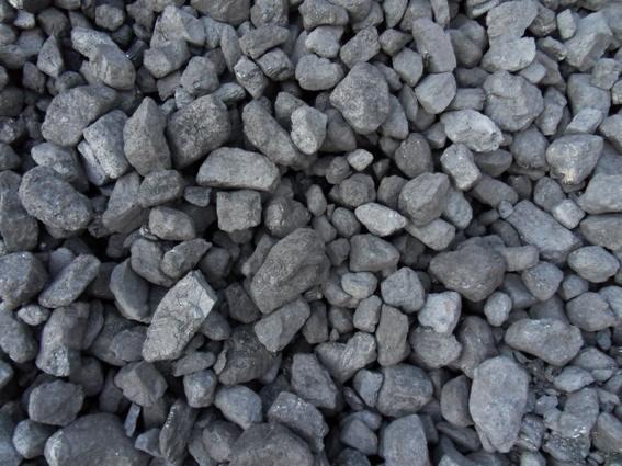 Góra brył węgla o nieregularnych kształtach, oświetlona z góry, ukazująca teksturę i odcienie szarości.