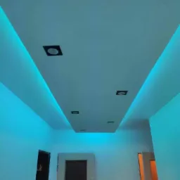 Nowoczesny sufit podwieszany z oświetleniem LED w kolorze turkusowym i wpuszczonymi oprawami halogenowymi, widok na korytarz z dwiema parami drzwi.