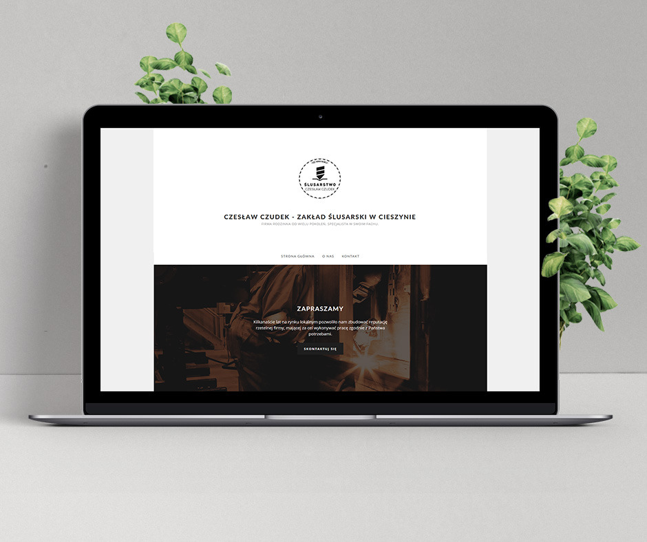 Laptop prezentuje stronę internetową zakładu ślusarskiego Czesław Czudek z Cieszyna, z minimalistycznym logo i ciemnym zdjęciem warsztatu w tle, otoczony dekoracyjnymi roślinami.