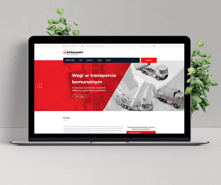 Ekran laptopa prezentujący stronę internetową firmy Pfreundt Polska, specjalizującej się w wagach do transportu komunalnego, z modelami hakowców, bramowców i śmieciarek na ilustracji, ustawiony...