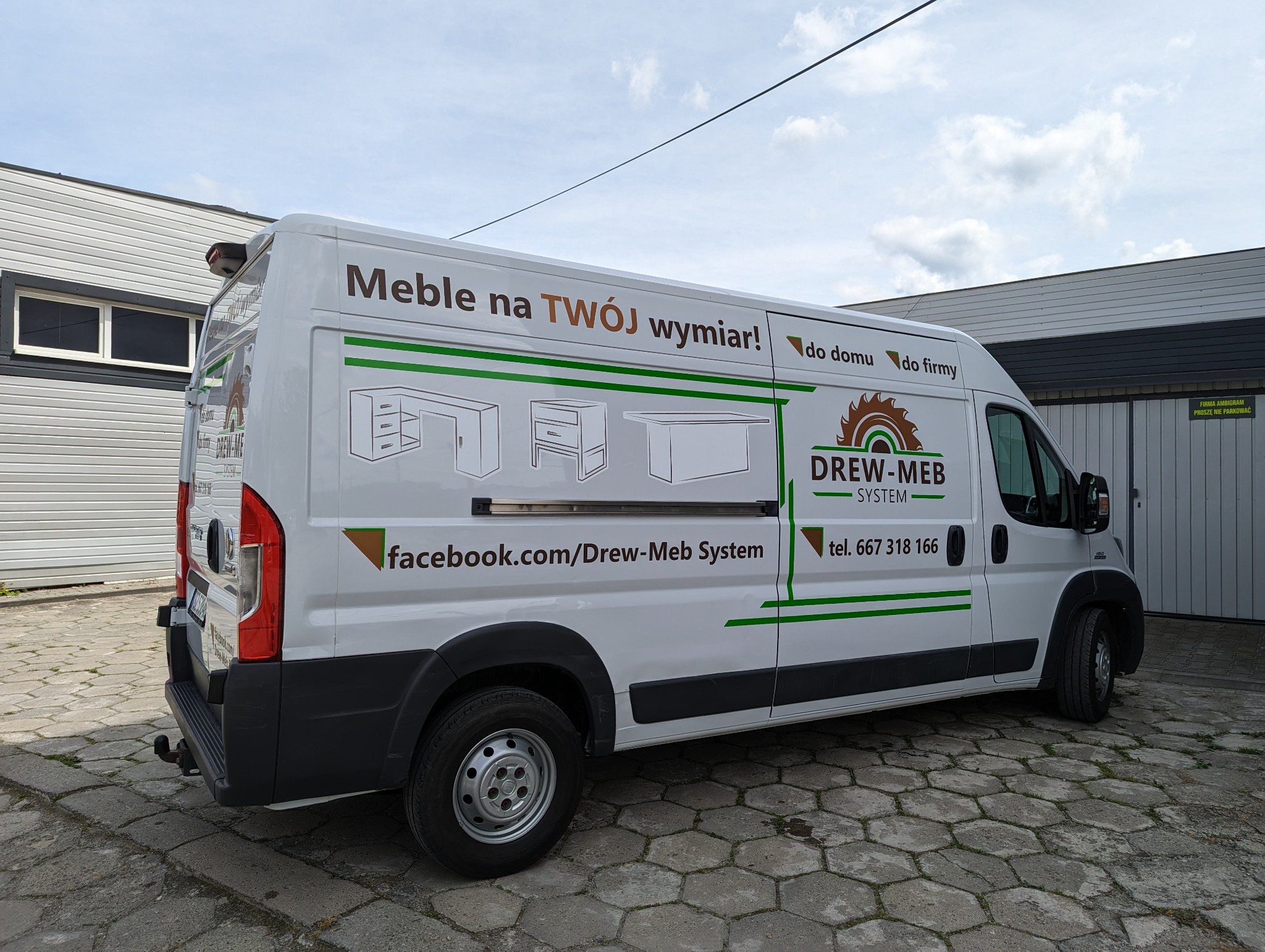 Biały samochód dostawczy z reklamą firmy Drew-Meb System, oferującej meble na wymiar do domu i firmy, z grafikami biurek i numerem telefonu.