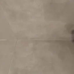 Beżowe płytki ceramiczne ułożone na podłodze, widoczne fugi i delikatna struktura płytek.