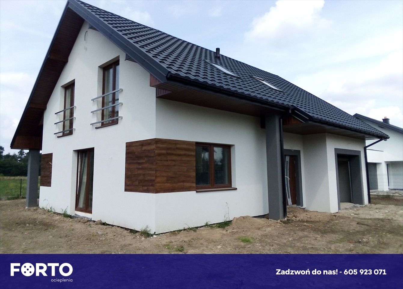 Nowoczesny dom jednorodzinny z białą elewacją, drewnianymi akcentami, ciemną dachówką i szarą stolarką okienną, widok z zewnątrz na etapie wykończenia terenu.