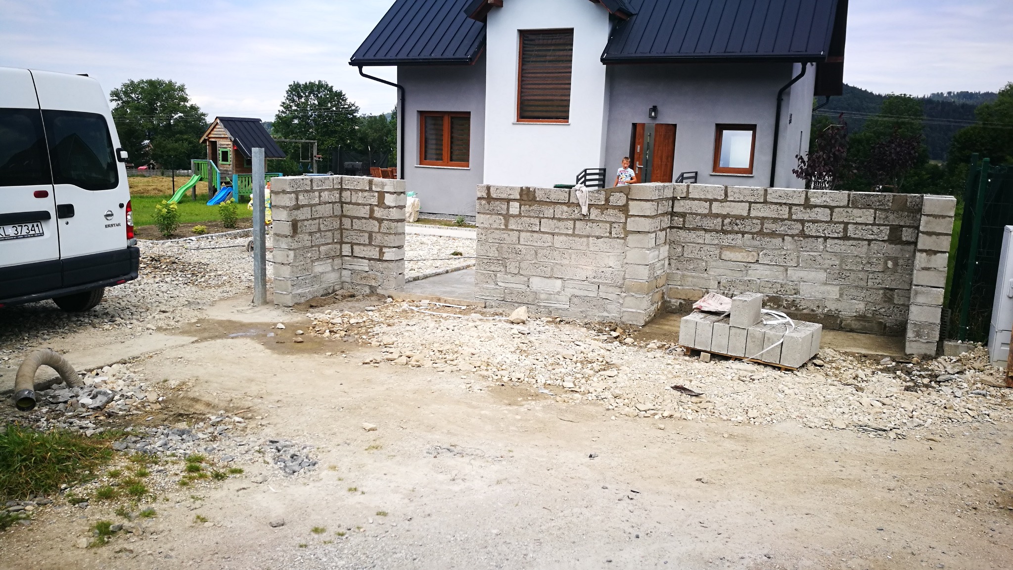 mur z bloczków betonowych pod oklejanie z kamienia naturalnego , w oddali kolejna realizacja czyli dom jednorodzinny