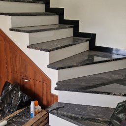 Ekipa Alana - Schody z czarnego granitu z białymi podstopnicami, częściowo wykończone, widoczne materiały budowlane i narzędzia pracy, realizacja we Wrocławiu.