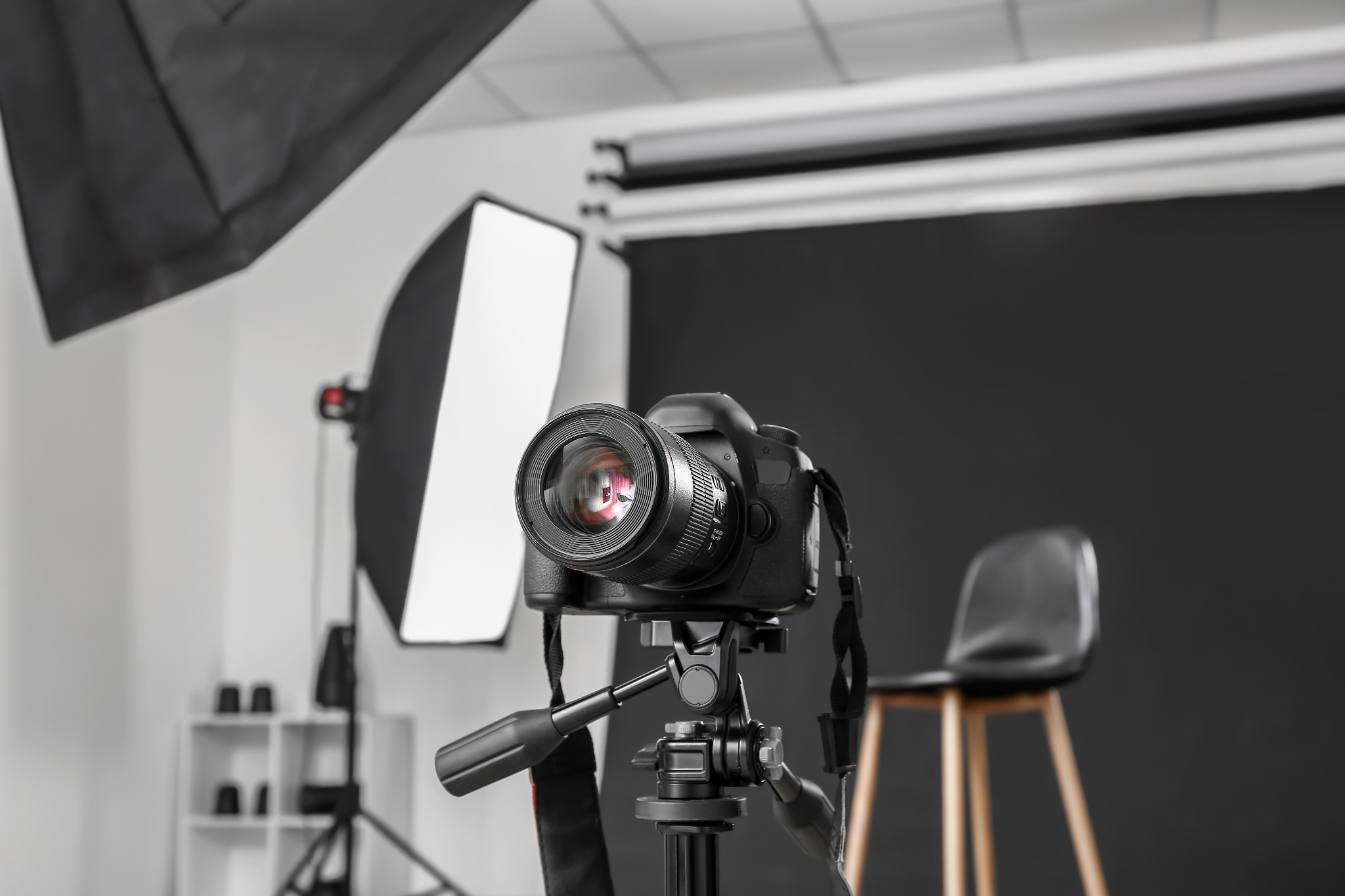 Profesjonalny aparat fotograficzny na statywie w studio, z softboxem i czarnym tłem, gotowy do sesji zdjęciowej.