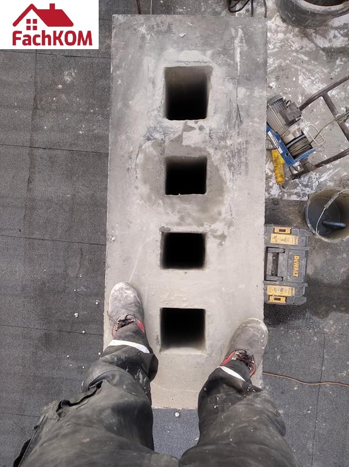 Betonowy moduł kominowy z czterema otworami, widok z góry, obok skrzynka narzędziowa DeWalt, w tle wciągarka linowa, robocze buty na module.