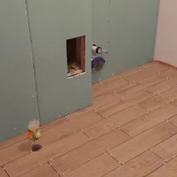 Podłoga w trakcie układania z płytek imitujących drewno, widoczne krzyżyki dystansowe, ściany przygotowane z płyt kartonowo-gipsowych, otwór w ścianie z widoczną izolacją, butelka po napoju...