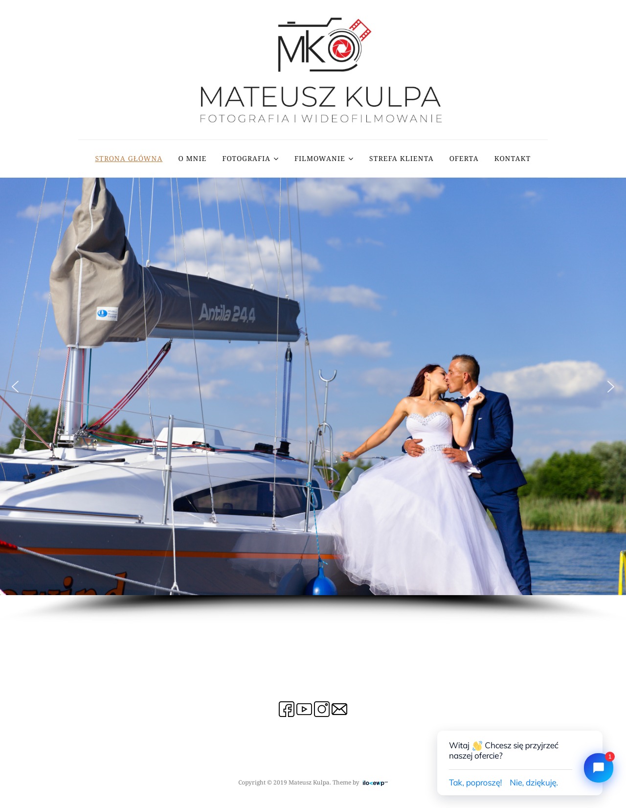 Para młoda w strojach ślubnych całuje się na pokładzie jachtu Antila 24.4, w tle woda i zieleń, zdjęcie zrealizowane przez firmę fotograficzną Mateusz Kulpa.