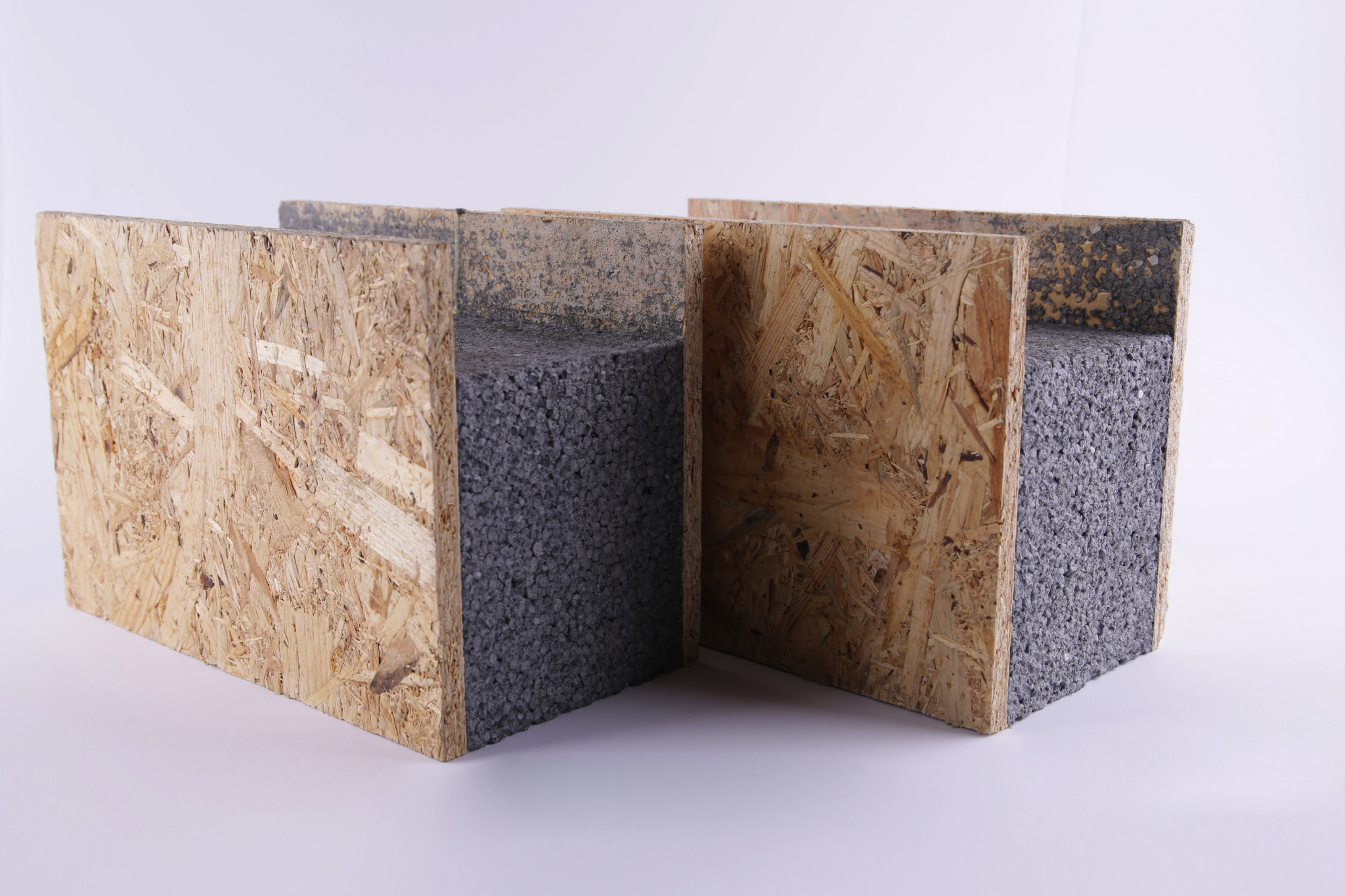 Dwa panele SIP z płyty OSB i szarego wypełnienia izolacyjnego, widoczne przekroje poprzeczne, na białym tle.