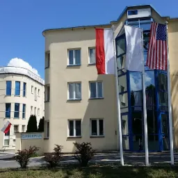 Budynek centrum rehabilitacji z flagami Polski i USA przed wejściem, widoczny napis 'Recepcja'.