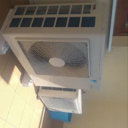 Dwa klimatyzatory Daikin zamontowane na balkonie w Ostrówku, z widocznym niebieskim wiadrem pod jednym z nich, prawdopodobnie podczas serwisu.