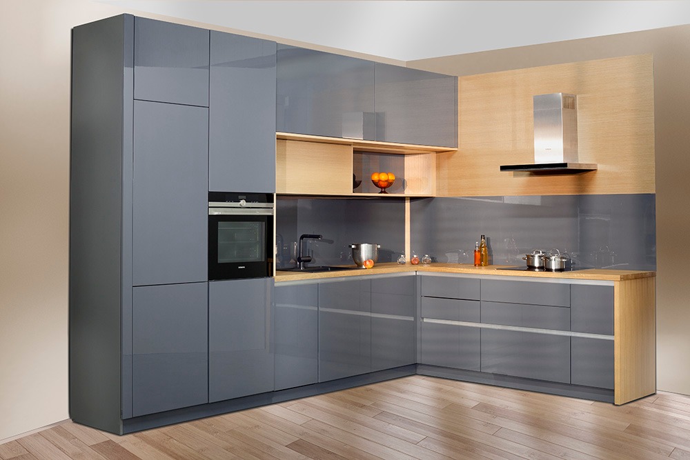 Nowoczesna, szara zabudowa kuchenna z lakierowanymi frontami, drewnianym blatem i wbudowanym piekarnikiem, uzupełniona o srebrny okap i owoce w misie.
