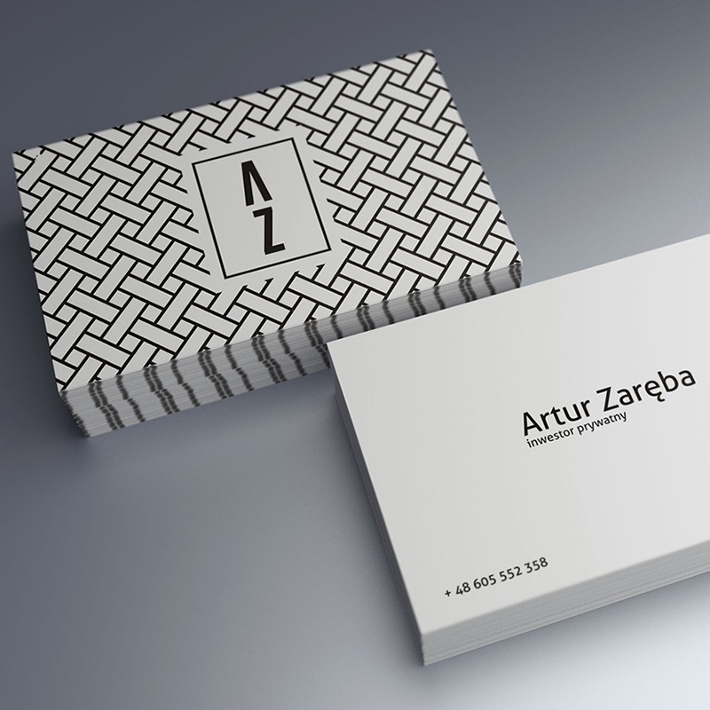Stos wizytówek z geometrycznym wzorem i logo 'AZ' obok wizytówki z danymi kontaktowymi Artura Zaręby, inwestora prywatnego, na gładkim szarym tle.