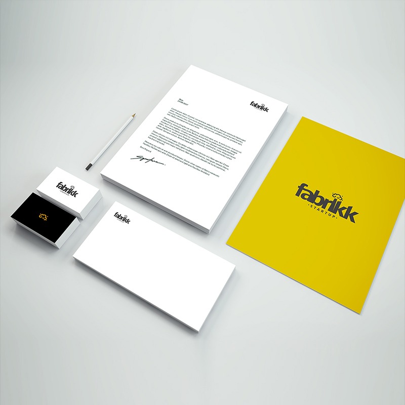 Komplet identyfikacji wizualnej firmy Fabrikk Startup: wizytówki, papier firmowy z podpisem, koperta i żółta teczka z logo, ułożone na jasnym tle.