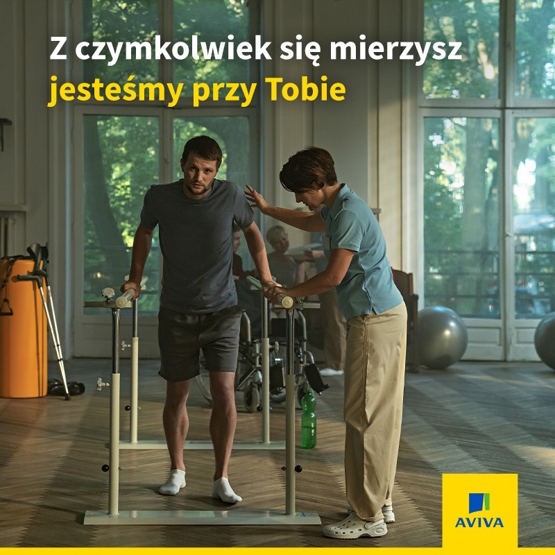Mężczyzna w trakcie rehabilitacji, wspierany przez terapeutę, z widocznym sprzętem rehabilitacyjnym i logo firmy ubezpieczeniowej w prawym dolnym rogu.
