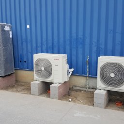 Klima-Rob Robert Majewski - Dwa zewnętrzne agregaty klimatyzacji Bosch ustawione na bloczkach betonowych przed niebieską ścianą kontenera, obok duży zbiornik w folii ochronnej i stos metalowych profili.