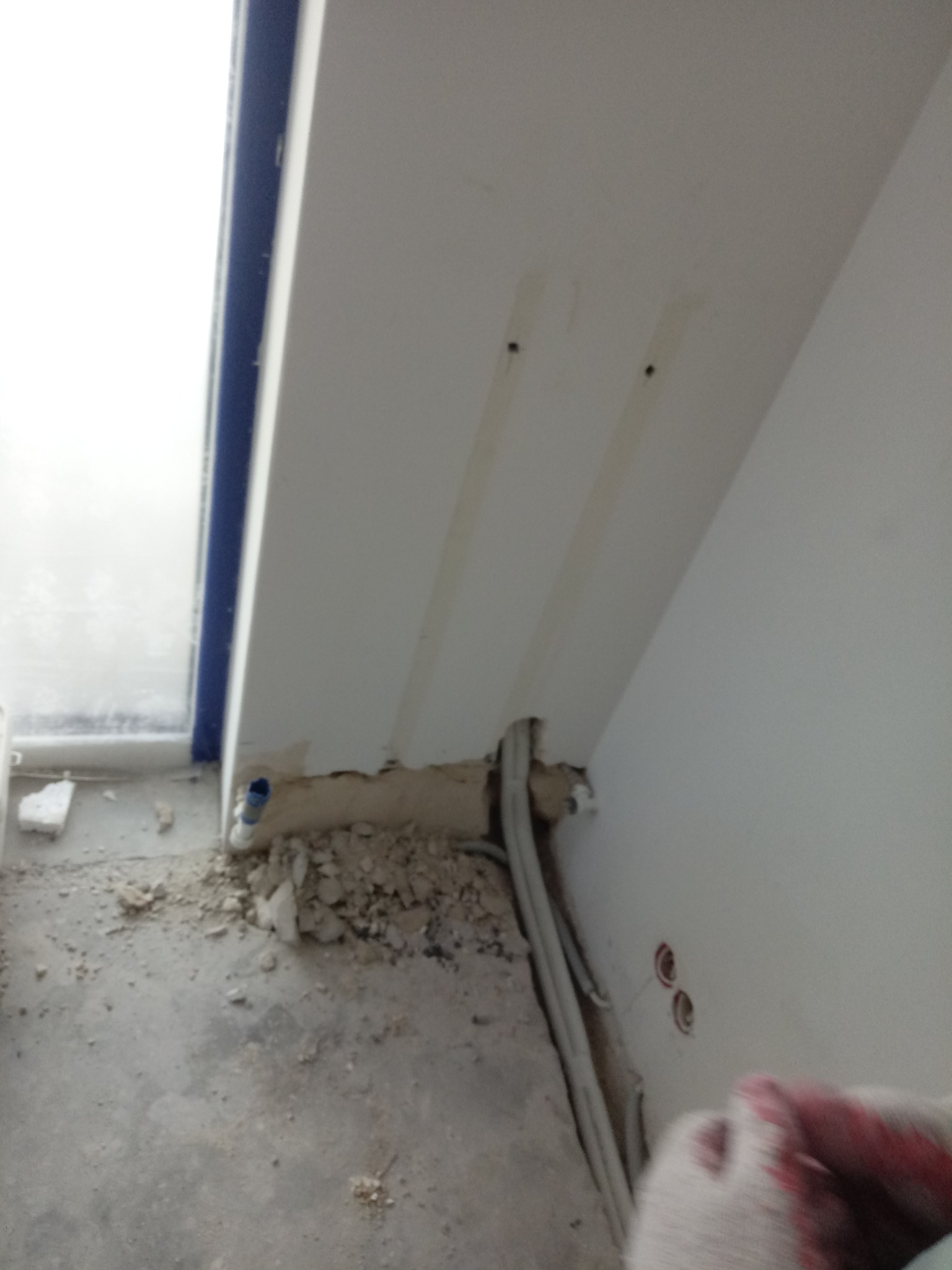 Montaż instalacji: widoczne przewody wystające ze ściany w trakcie prac przygotowawczych, ślady wiercenia, instalacja przy oknie.