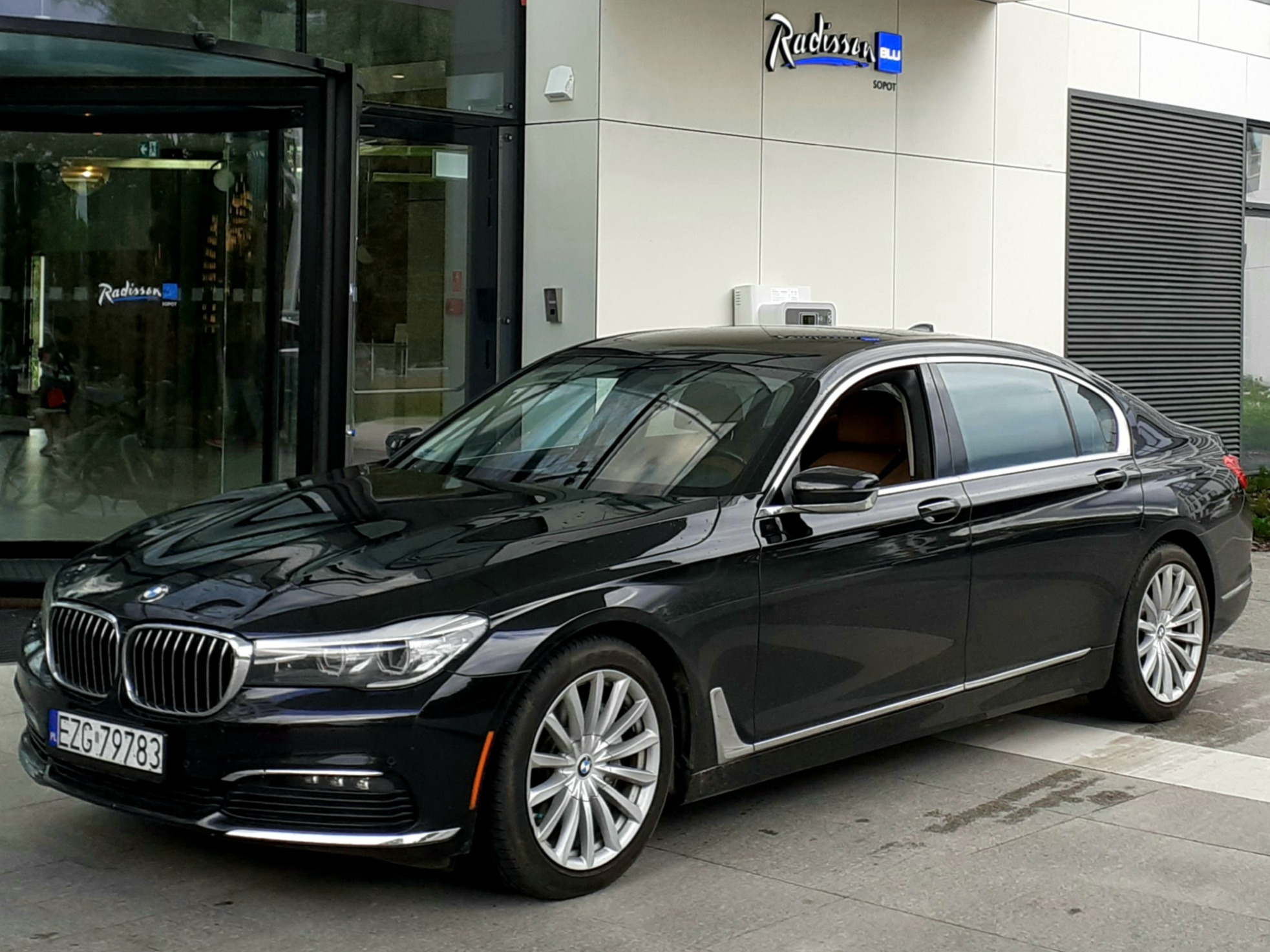 Czarna limuzyna BMW serii 7 z numerem rejestracyjnym EZG 79783 zaparkowana przed wejściem do hotelu Radisson Blu w Sopocie.