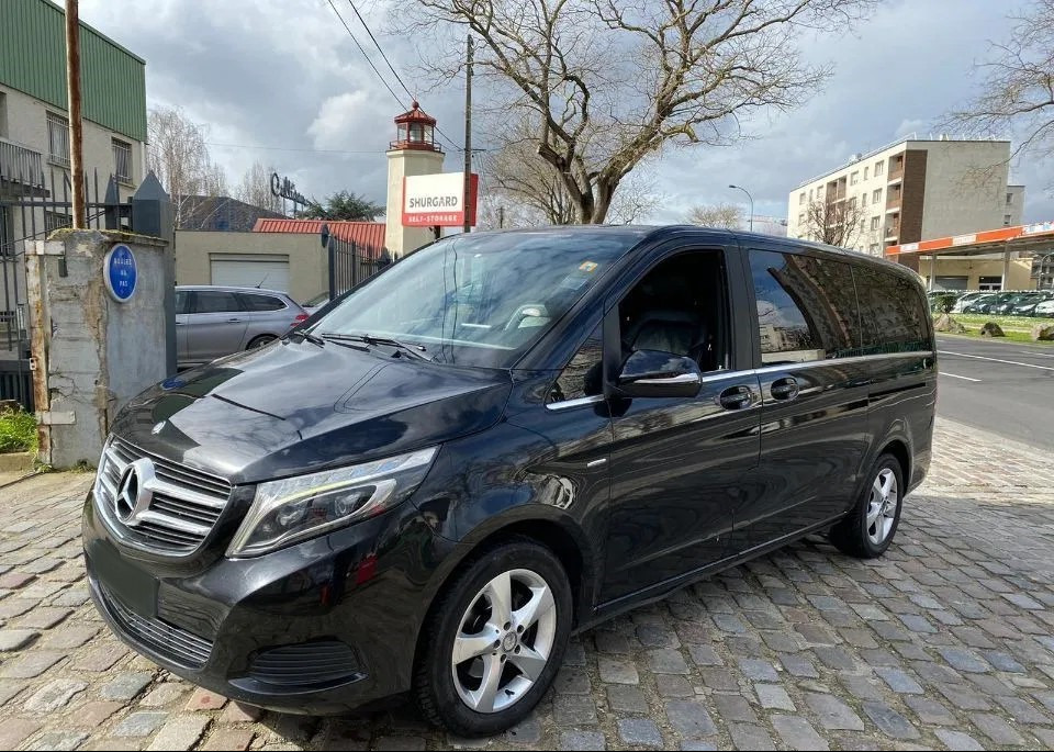 Czarny Mercedes-Benz V-Class zaparkowany na brukowanej ulicy, z budynkiem Shurgard w tle.