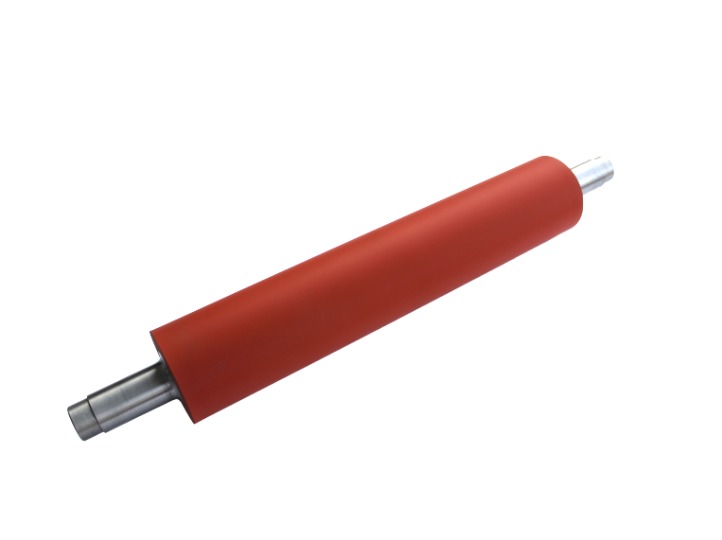 Czerwony wałek z metalowymi osiami na białym tle, prawdopodobnie element maszyny do obróbki.