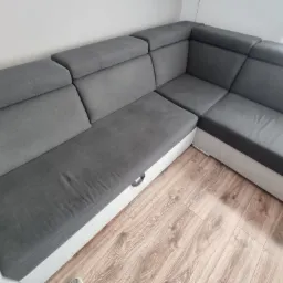 Szary narożnik z pojemnikiem na pościel, widok z góry na drewnianą podłogę.