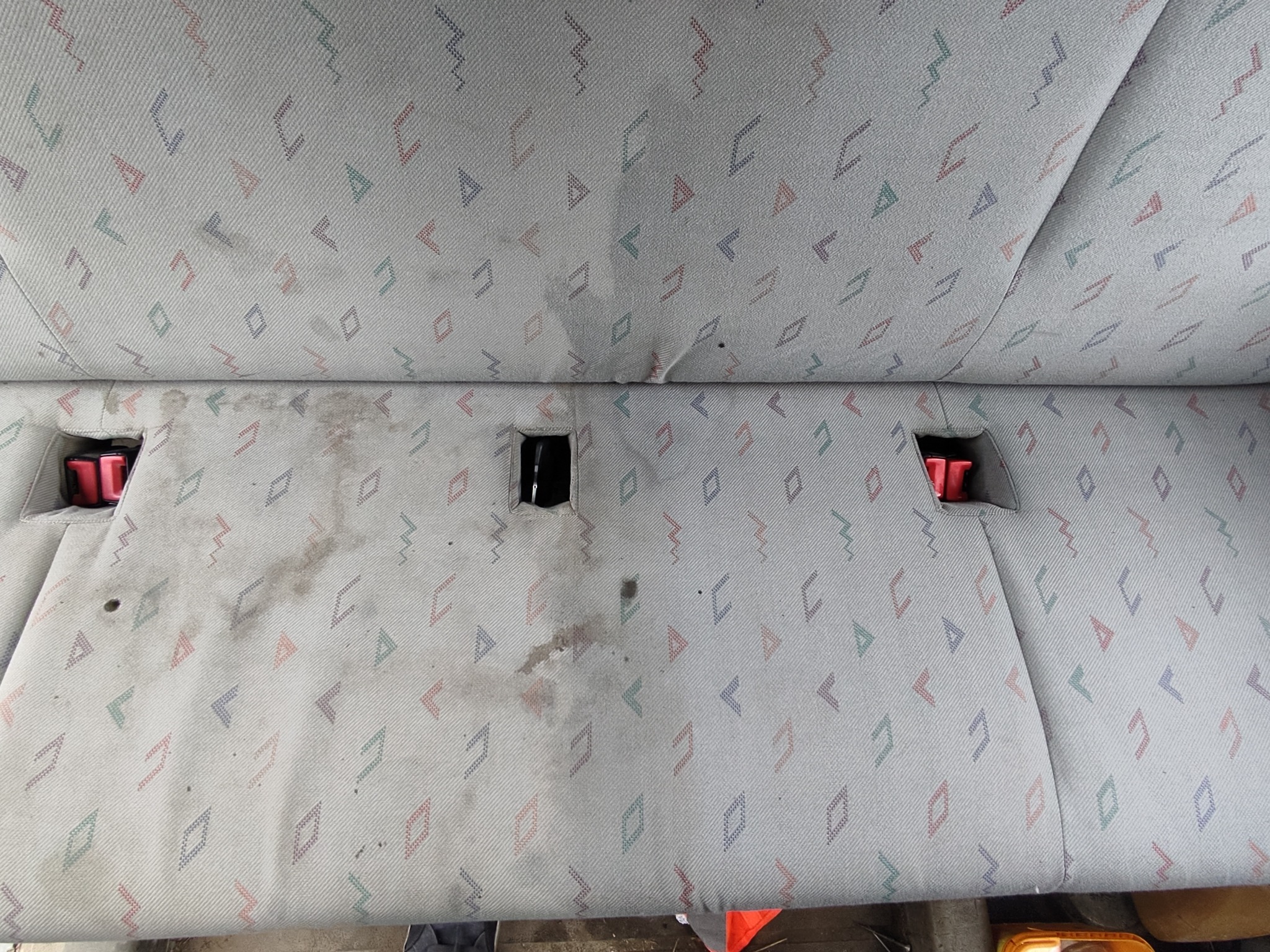 Brudna, jasna tapicerka samochodowa z geometrycznym wzorem przed czyszczeniem w Łubianie, widoczne plamy i zabrudzenia.