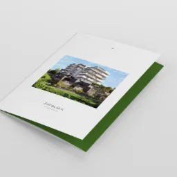 Otwarta broszura z wizualizacją apartamentowca ZAPOLSKA na okładce, z zielonym wnętrzem, leżąca na jasnoszarym tle.