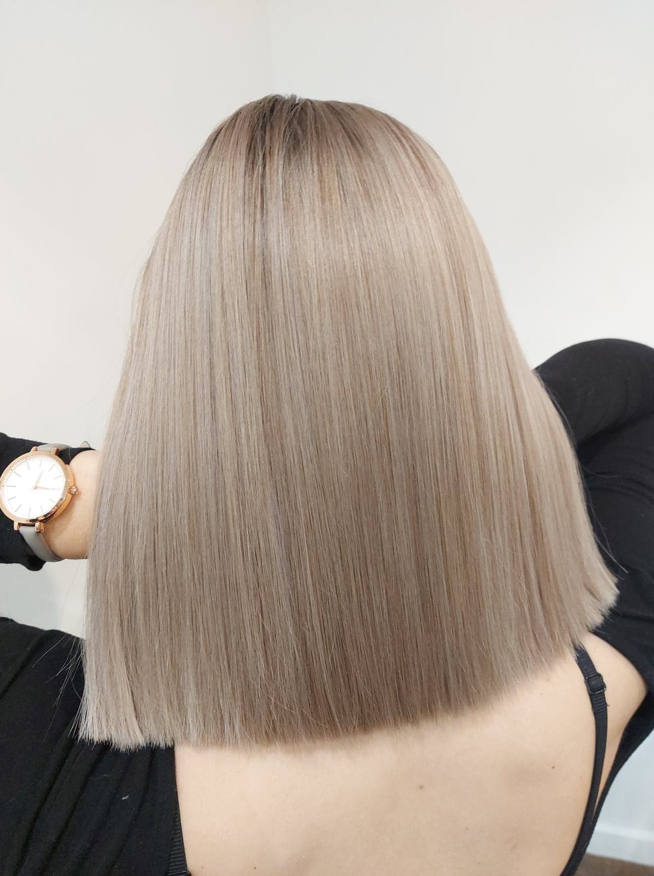 Proste, popielate włosy do ramion, widok z tyłu, z zegarkiem na nadgarstku.