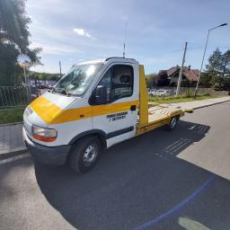 Adek-trans - Żółto-biała laweta z napisem 'POMOC DROGOWA' zaparkowana na asfalcie w słoneczny dzień, widok z boku.