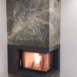 Nowoczesny kominek narożny, obudowa wykonana z kamienia Forest Green oraz Nero