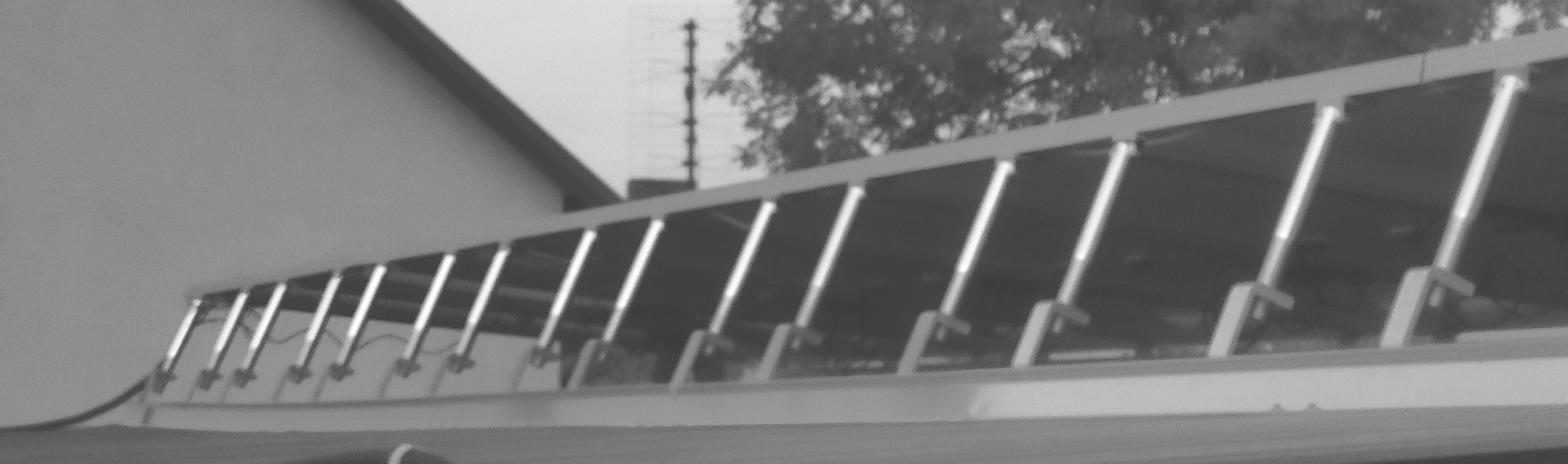 Instalacja fotowoltaiczna na dachu krytym blachą, z modułami podniesionymi na wspornikach skierowanymi na południe, widok z boku.