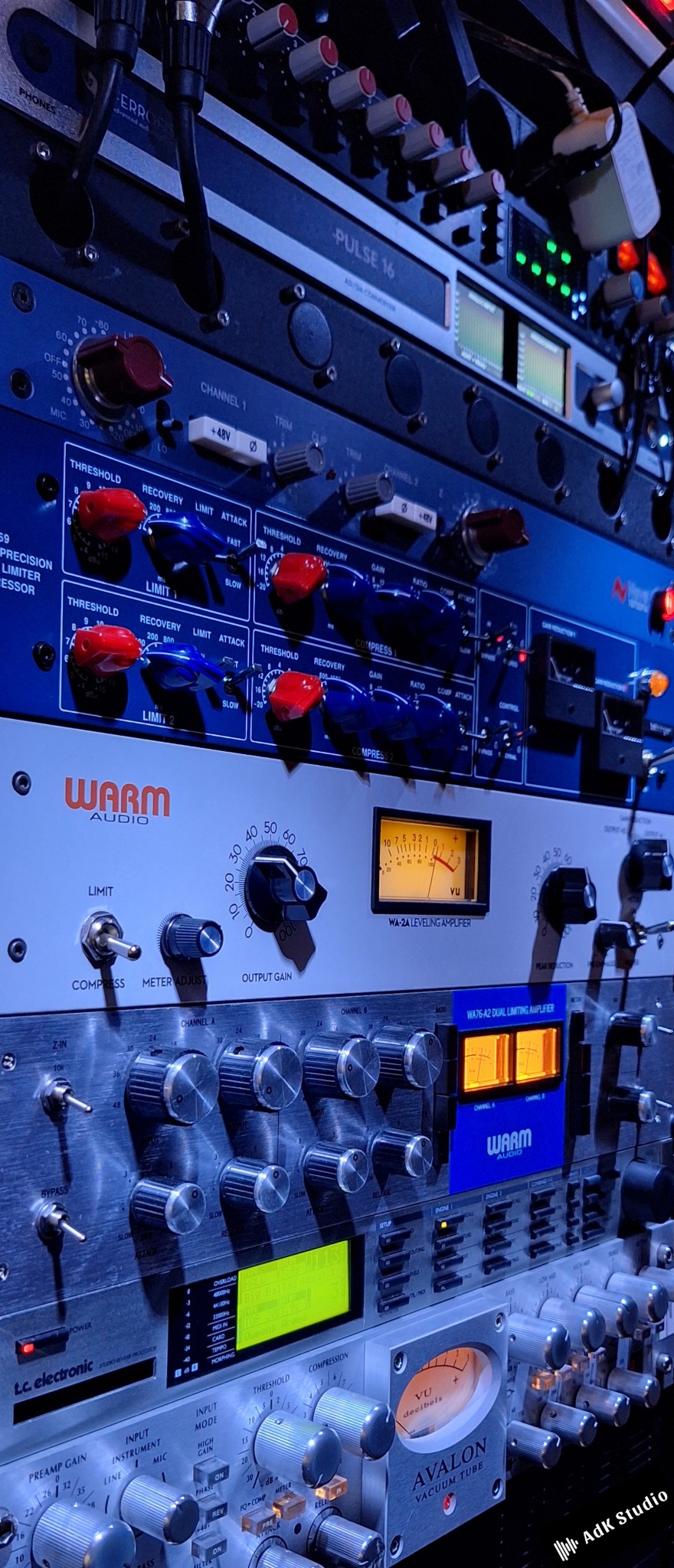 Sprzęt studyjny: mikser, kompresory Warm Audio i Avalon, procesor efektów TC Electronic. Widok na pokrętła, wskaźniki VU i wyświetlacze.