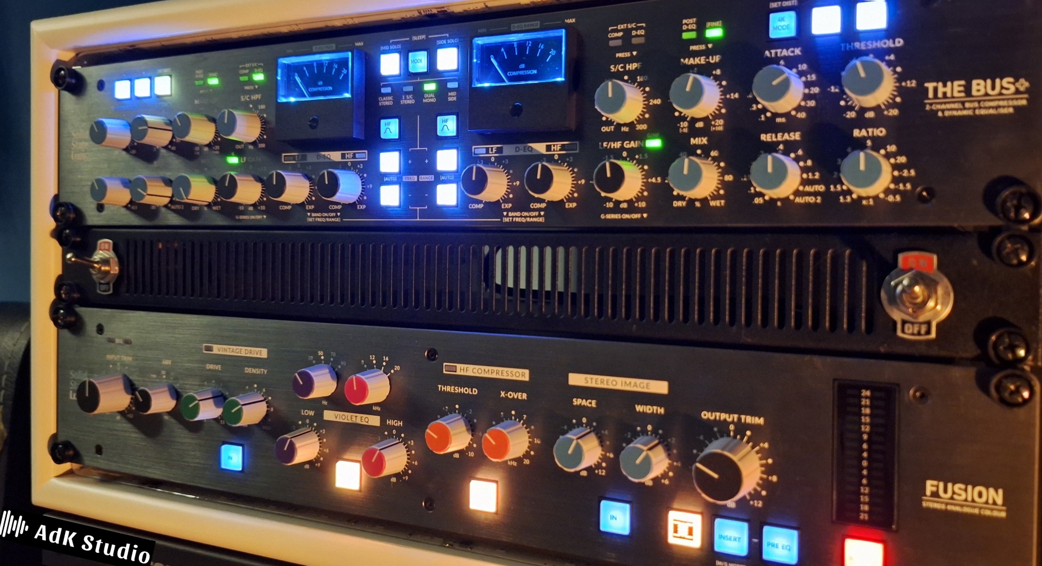 Profesjonalny sprzęt studyjny: kompresory i equalizery z podświetlanymi wskaźnikami, tworzące zaawansowany system do obróbki dźwięku w  studiu nagrań.